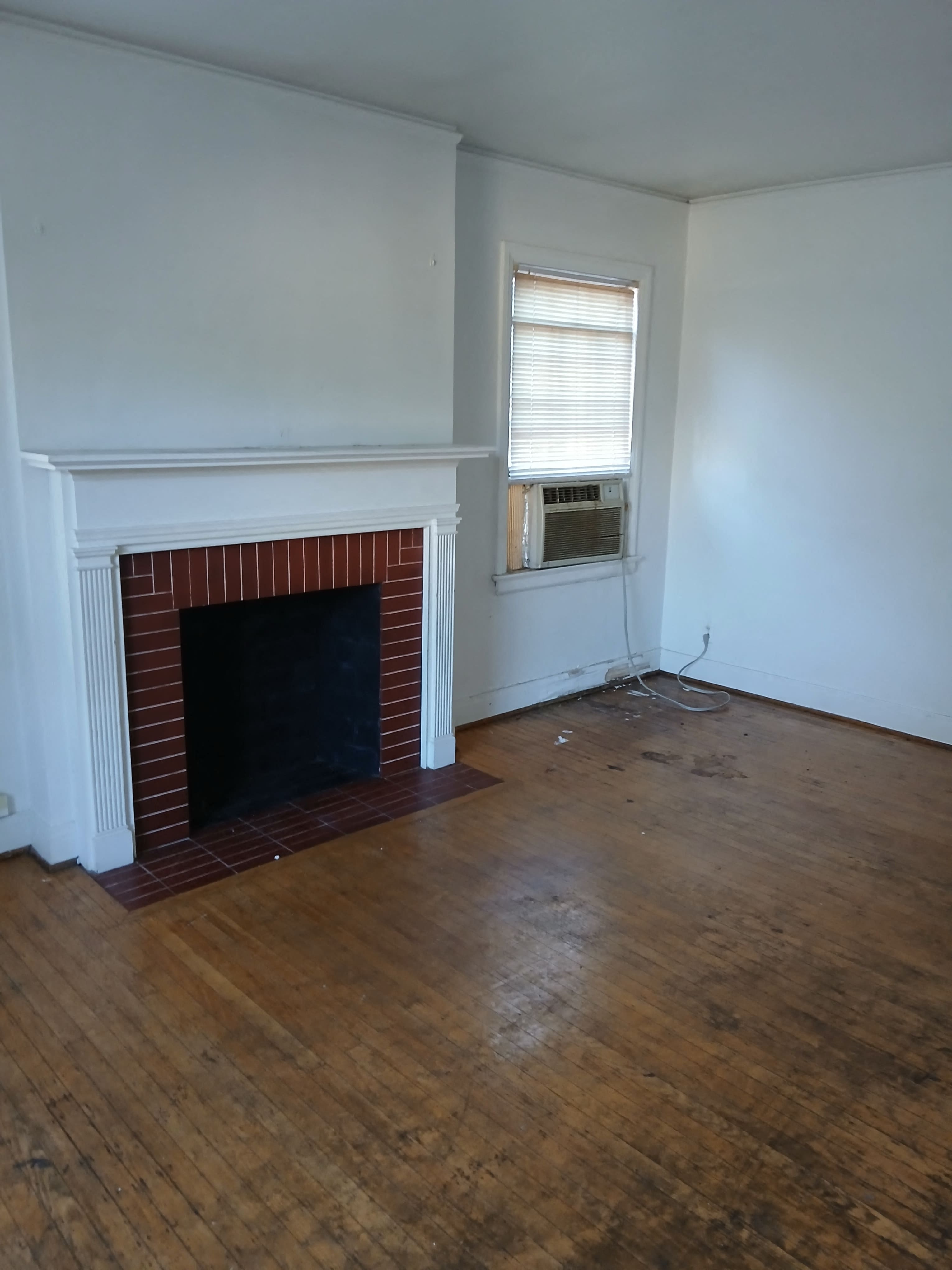 an empty living room with a fireplace and wooden floors