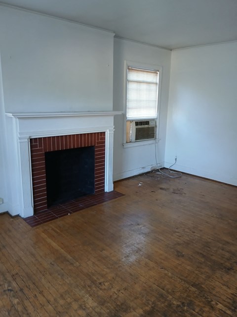 an empty living room with a fireplace and wooden floors