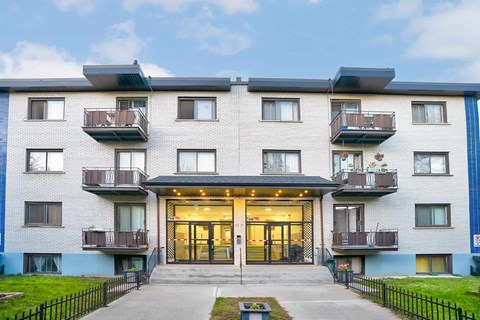 A modern apartment building with a black fence in front.