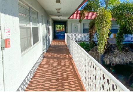 a porch with a white railing and a building with palm trees