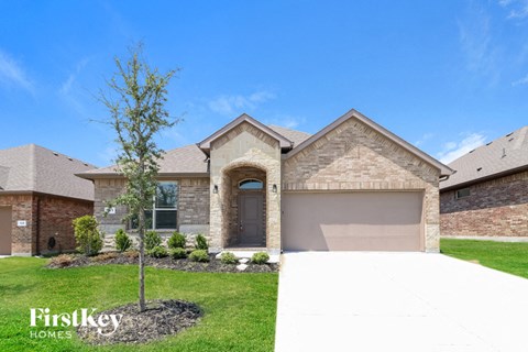 A house with a garage and a tree in the front yard.
