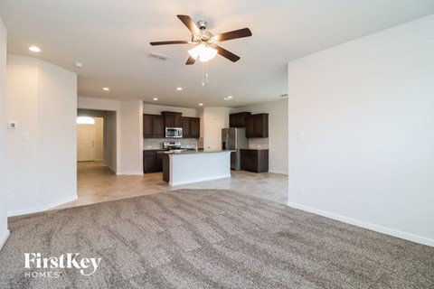 A spacious living room with a carpeted floor and a ceiling fan.
