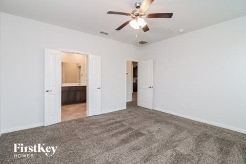 A spacious room with a carpeted floor and a ceiling fan.