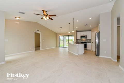 A spacious kitchen and living room with a ceiling fan and lighting fixtures.