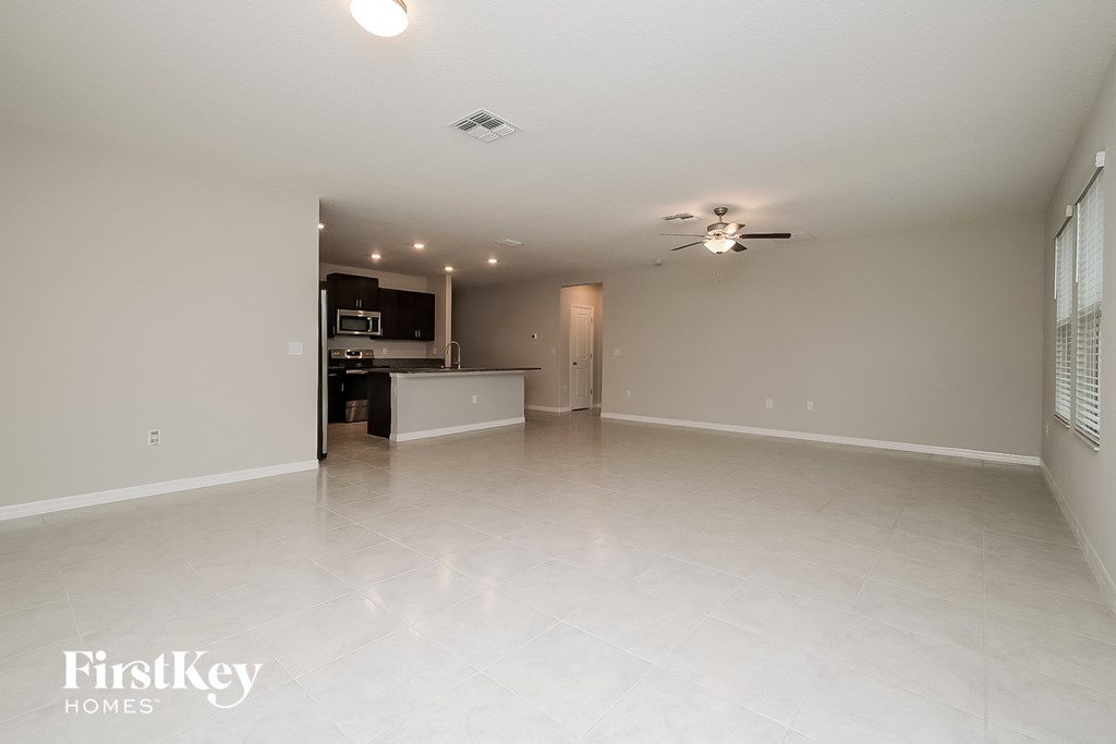 an empty living room and kitchen with a ceiling fan