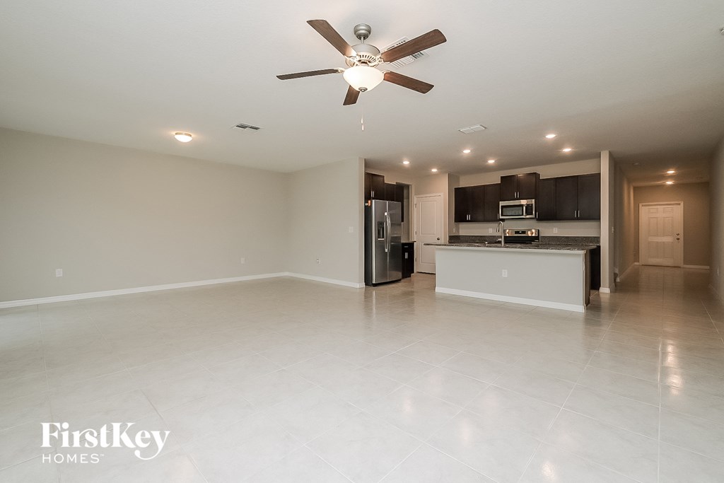 an empty living room and kitchen with a ceiling fan