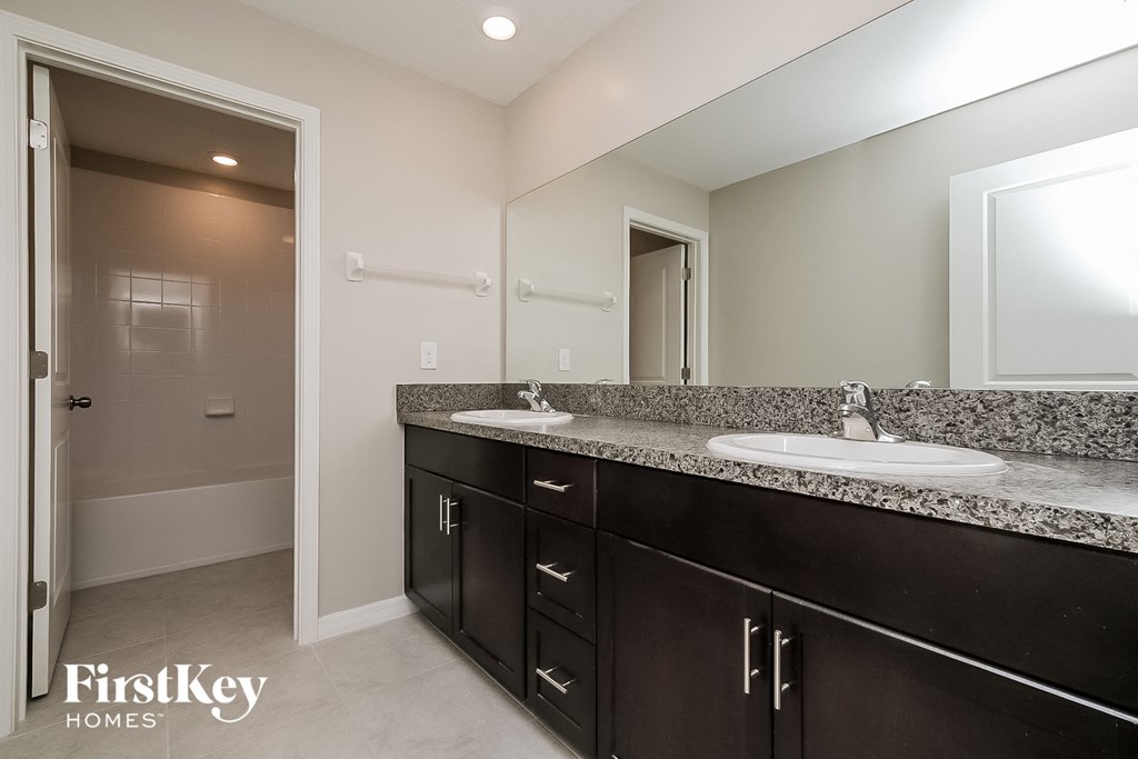 the master bathroom has dual sinks and a large mirror
