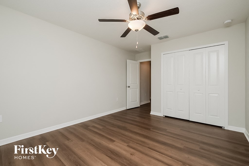 a bedroom with a ceiling fan and a door to a closet
