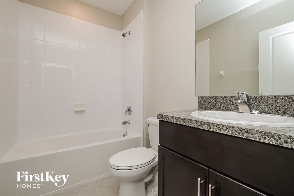 a bathroom with a toilet sink and tub and a mirror