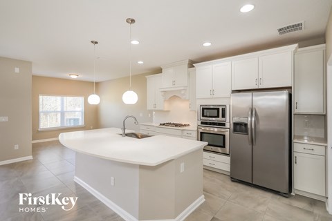 a large white kitchen with stainless steel appliances and white counter tops