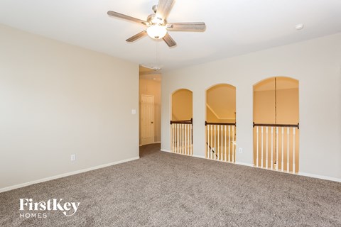 a spacious living room with carpet and a ceiling fan