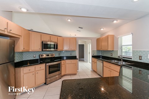 a kitchen with black counter tops and wooden cabinets