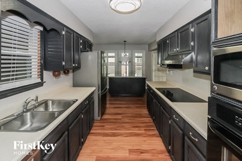 A kitchen with black cabinets and a wooden floor.