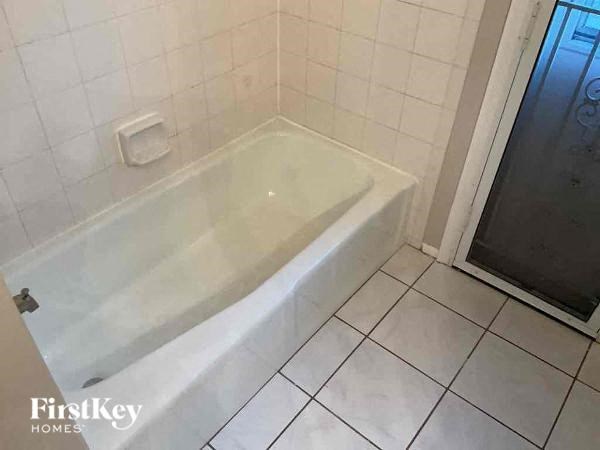 a white bath tub in a white tiled bathroom