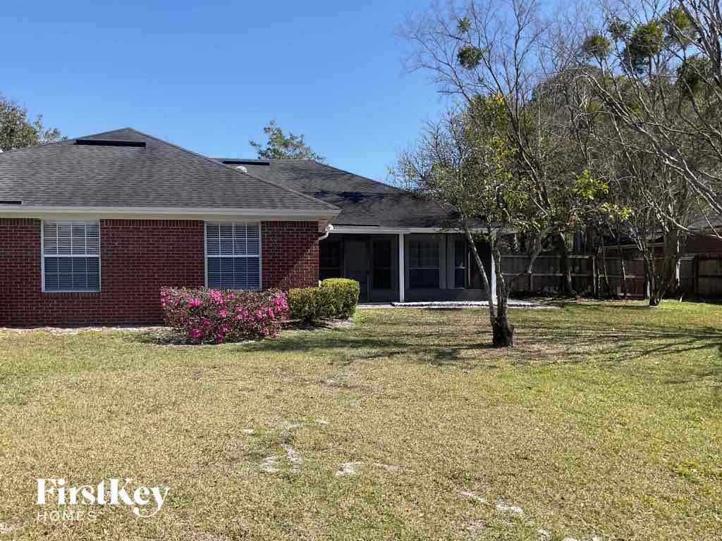 the front of a brick house with a yard and a tree