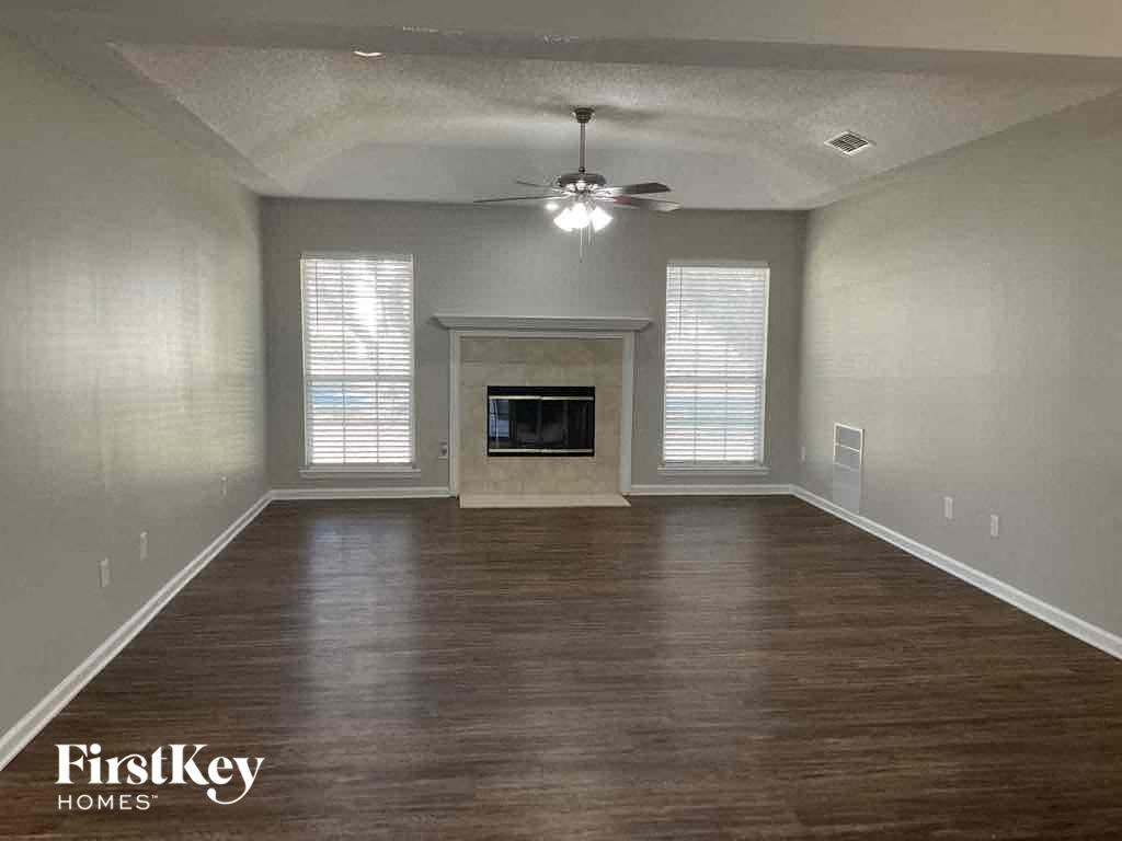 an empty living room with a ceiling fan and a fireplace