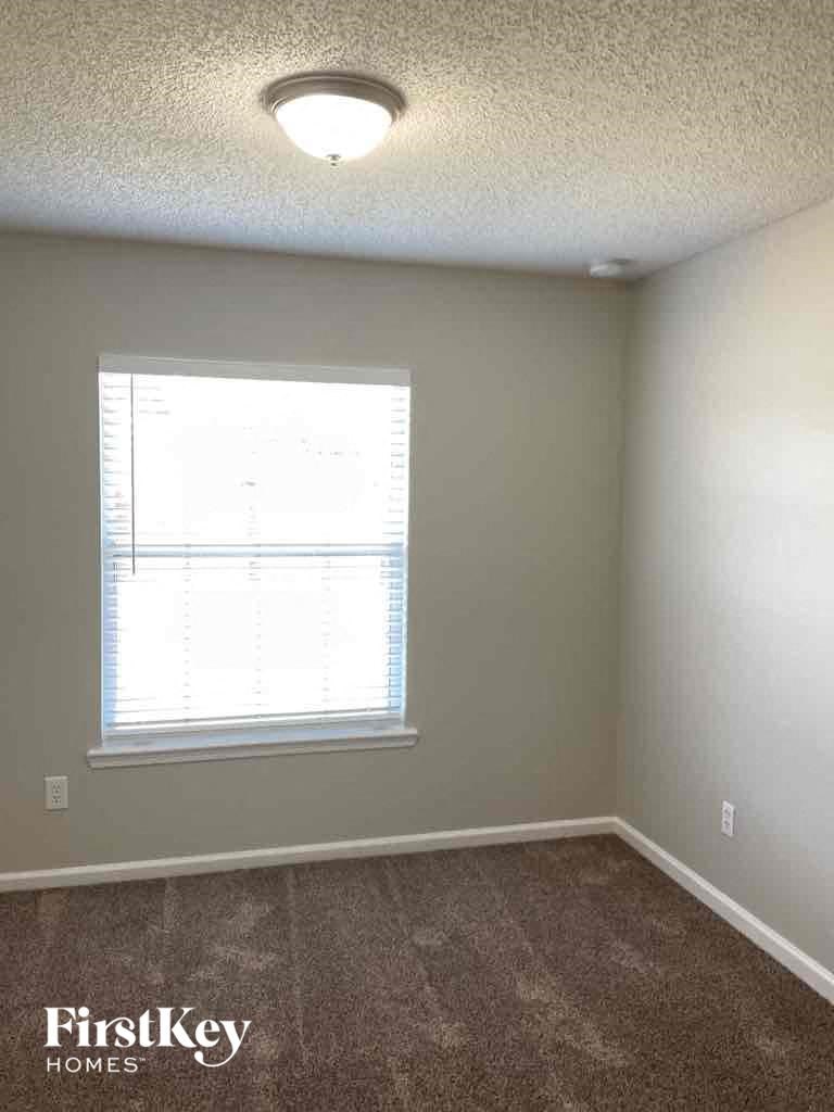 an empty room with a window and a carpeted floor