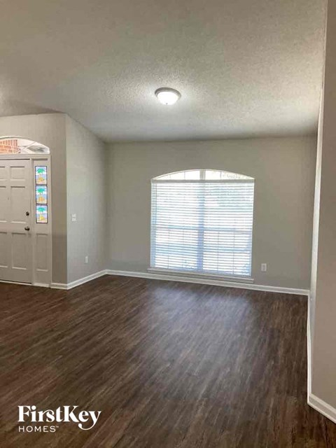 an empty living room with wood floors and a window