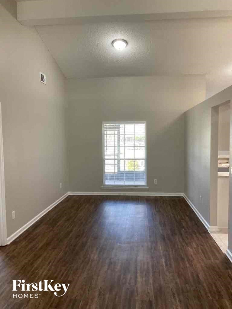 an empty living room with wood floors and a window