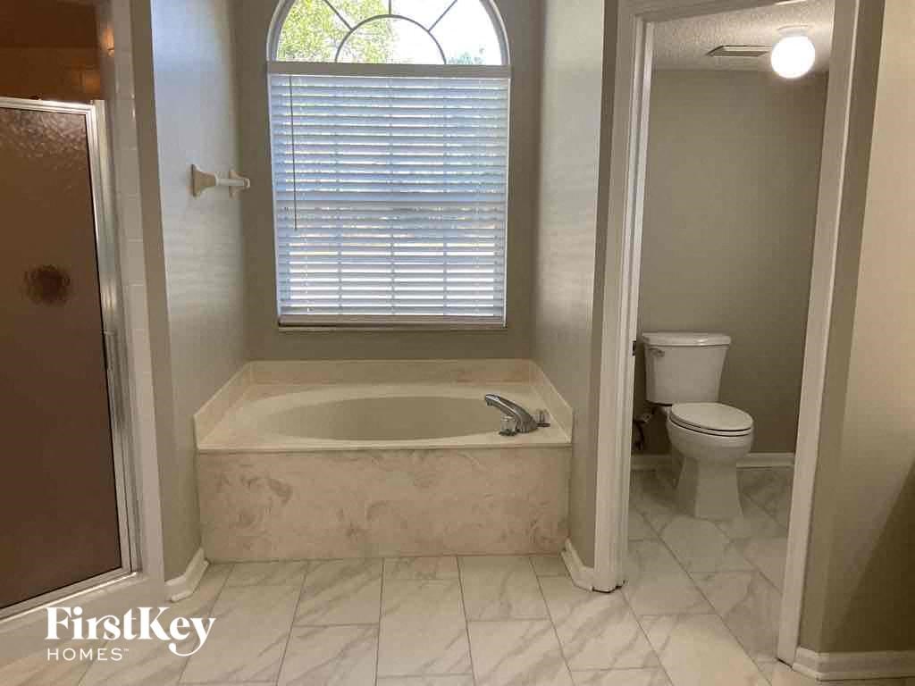 a bathroom with a tub and a toilet and a window