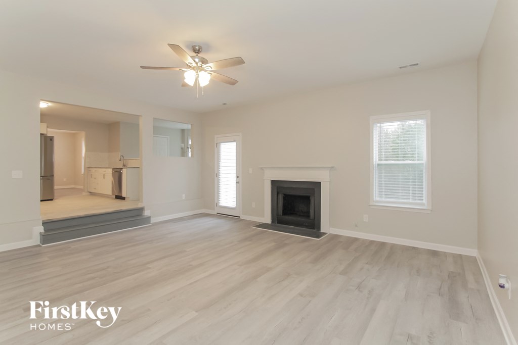 an empty living room with a fireplace and a ceiling fan