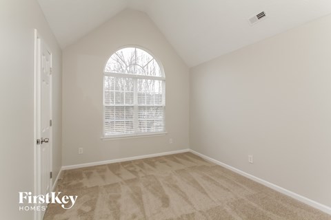 the second bedroom is spacious and clean with vaulted ceilings and a large window