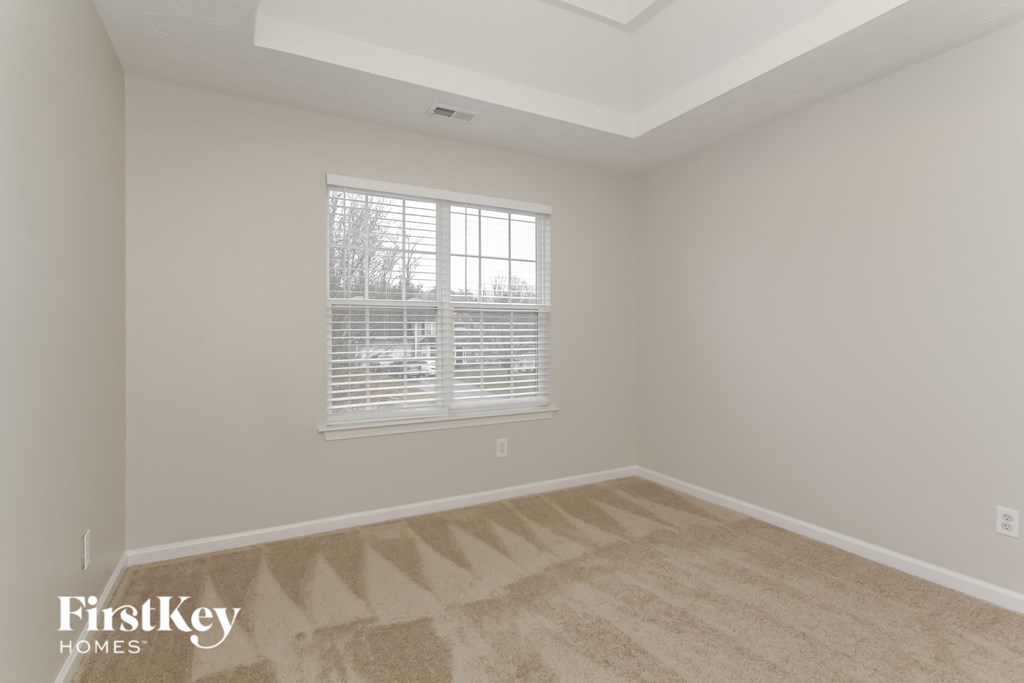 the living room of a home with a large window and carpeting