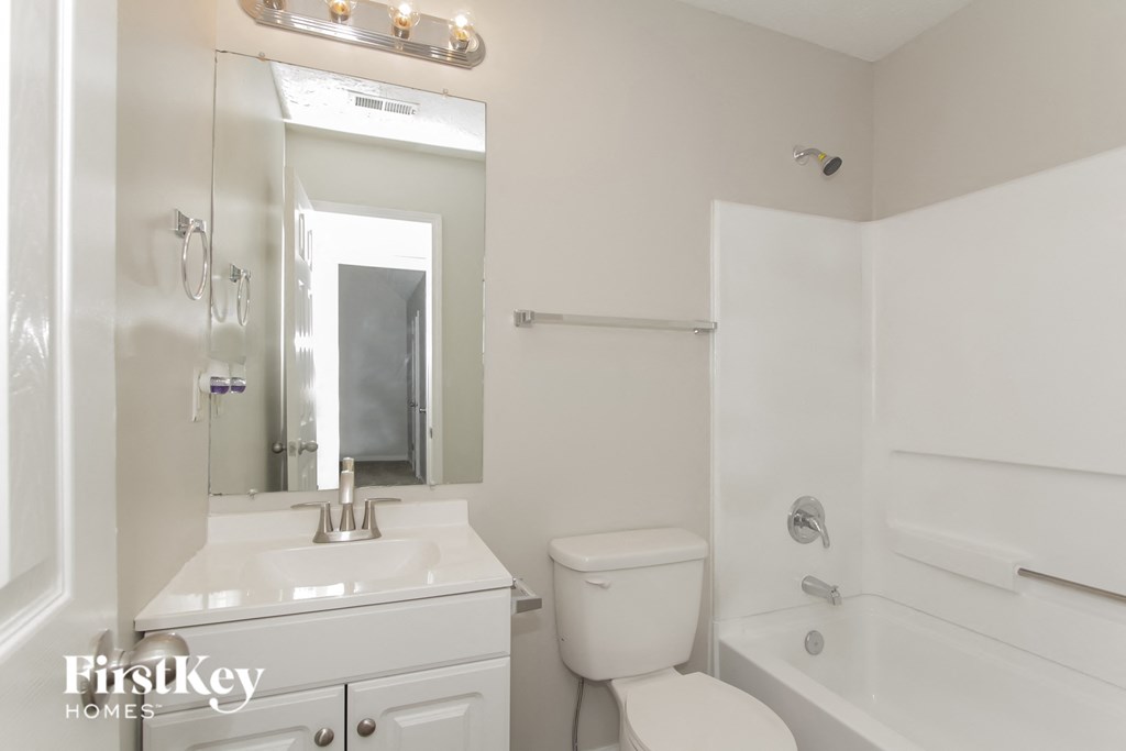 a white bathroom with a large mirror and a white toilet and sink