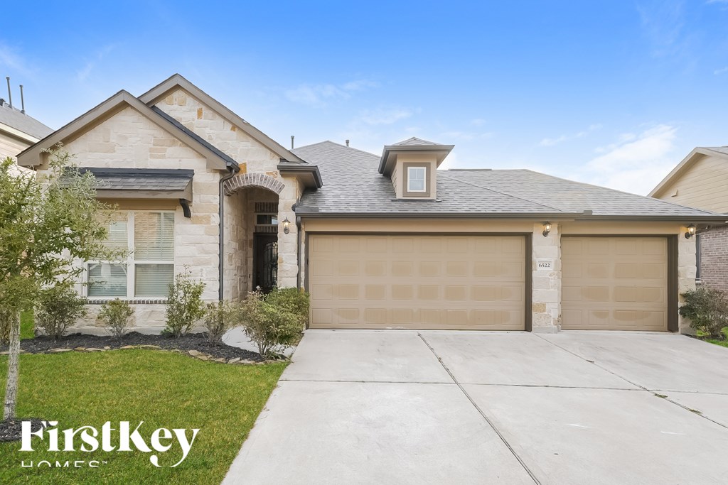 A house with a garage door and a tree in front of it.