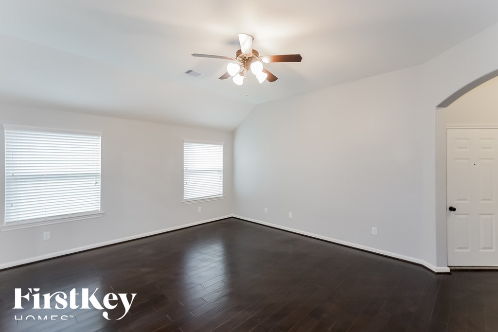 A spacious room with a ceiling fan and wooden flooring.