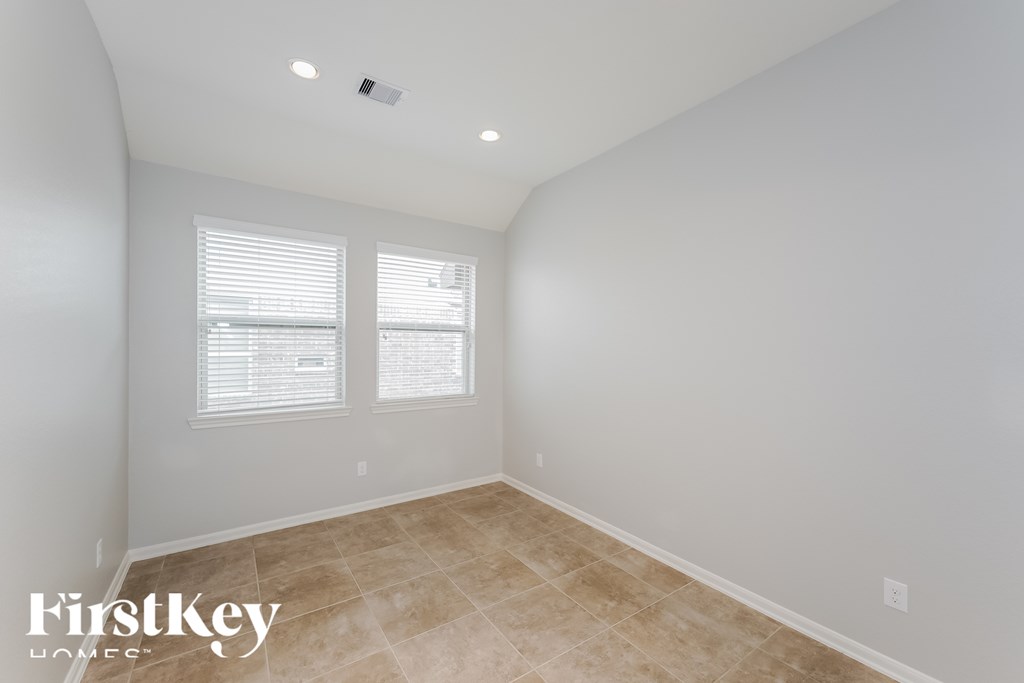 A room with a tiled floor and two windows.