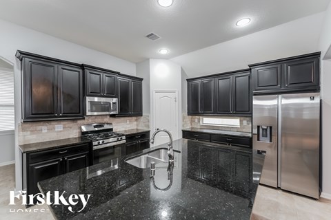 A modern kitchen with black cabinets and stainless steel appliances.
