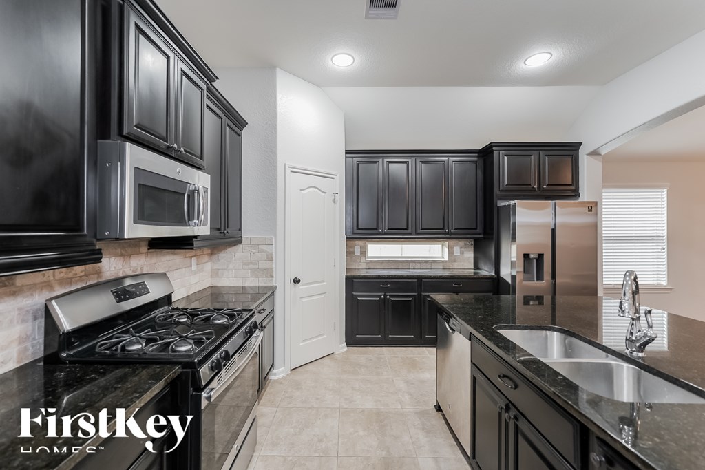 A kitchen with black cabinets and a stove top oven.