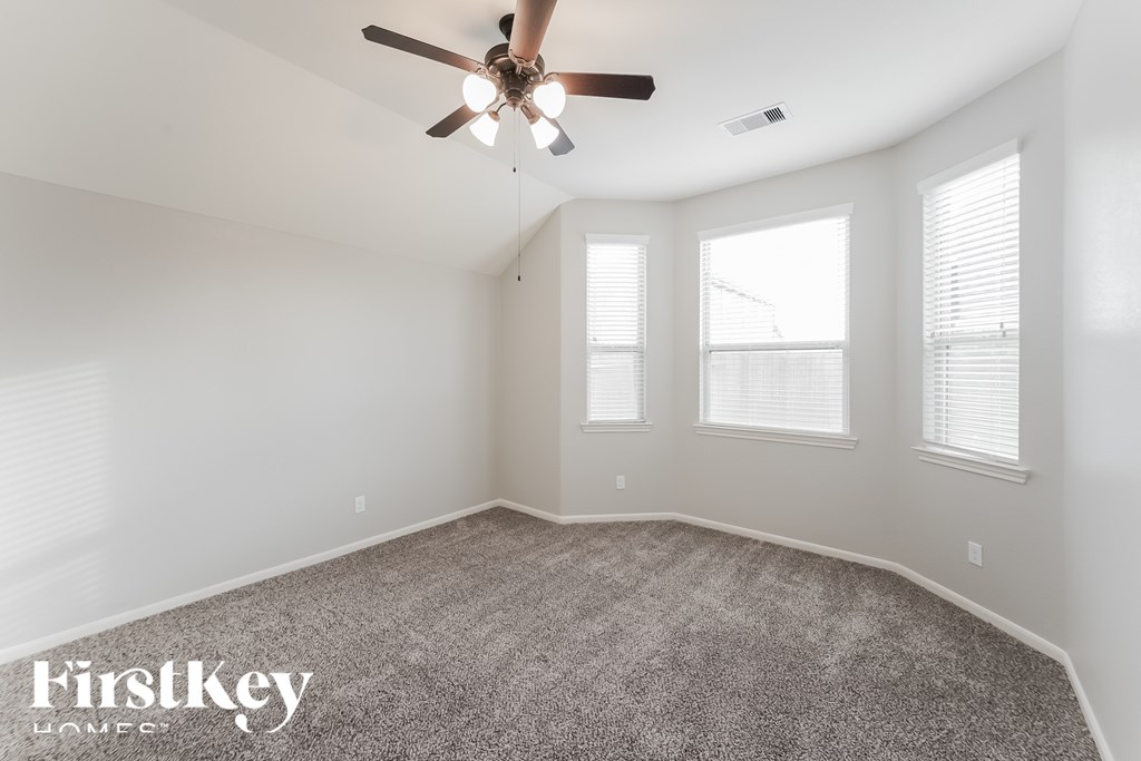 A spacious room with a ceiling fan and carpeted floor.
