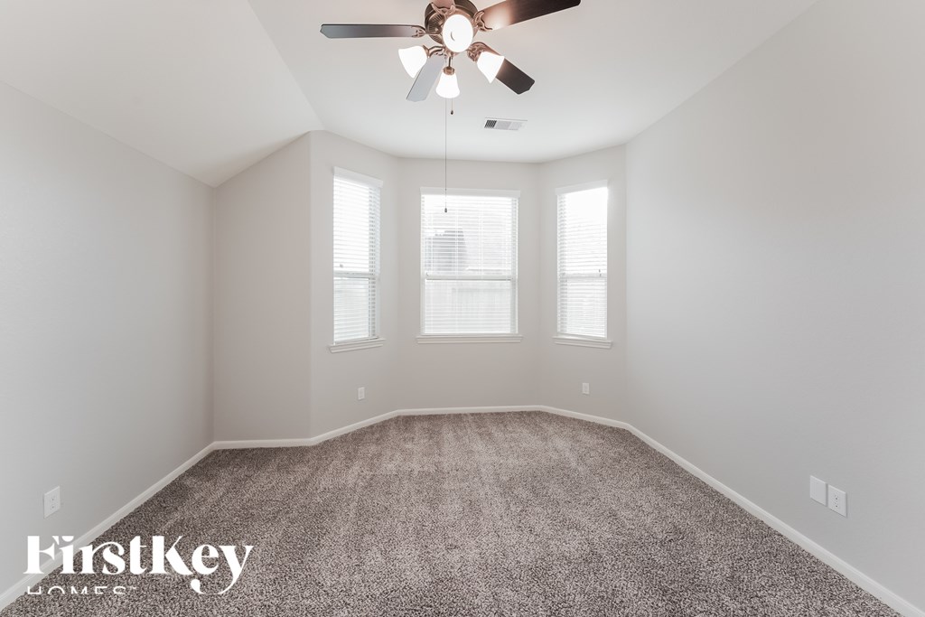 A spacious room with a ceiling fan and carpeted floor.