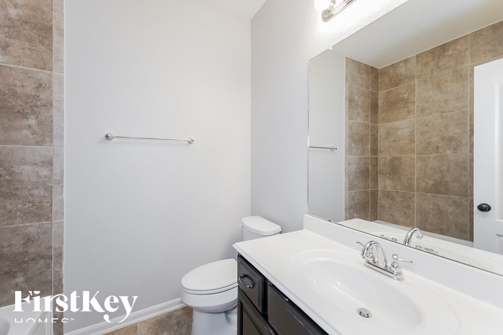 A bathroom with a toilet, sink, and mirror.