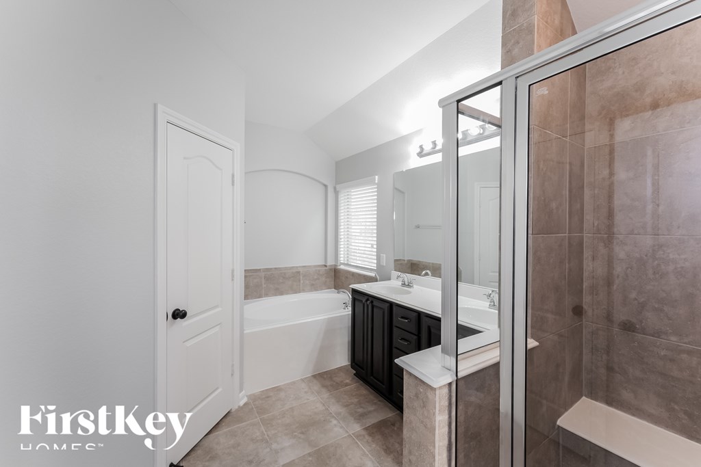 A bathroom with a tub, sink, and mirror.