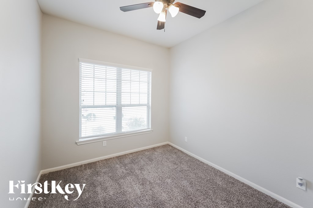 A room with a ceiling fan and a window with blinds.