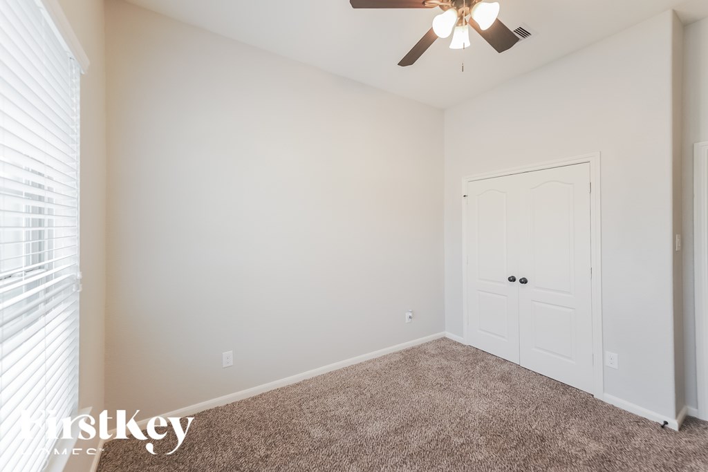 A room with a ceiling fan and a white door.