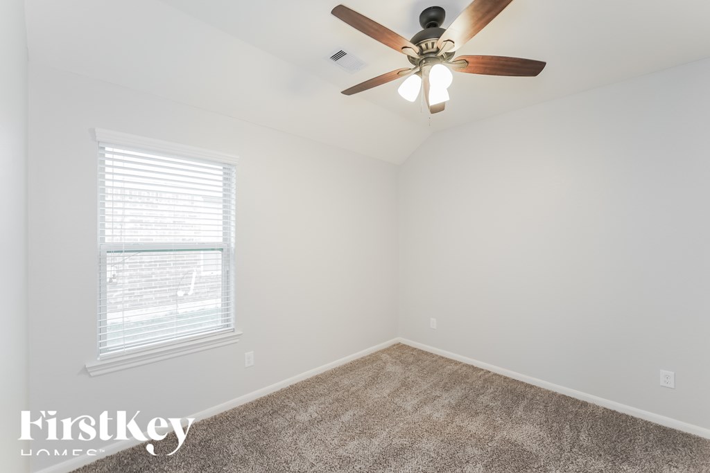 A room with a ceiling fan and a window with blinds.
