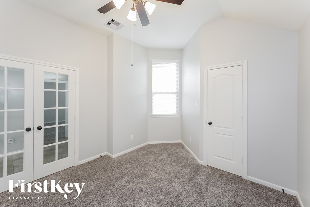 A spacious room with a ceiling fan and a window letting in natural light.