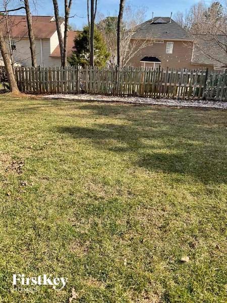 A grassy area with a wooden fence and houses in the background.