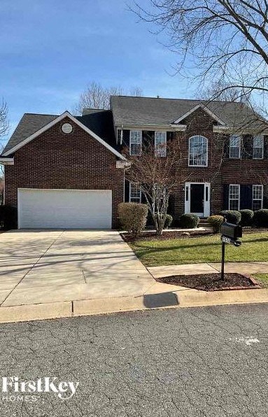 A brick house with a white garage door and a mailbox on the lawn.