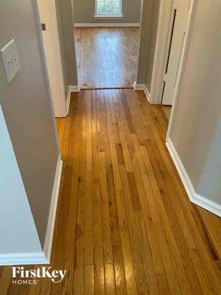 A hallway with wooden floors and white walls.