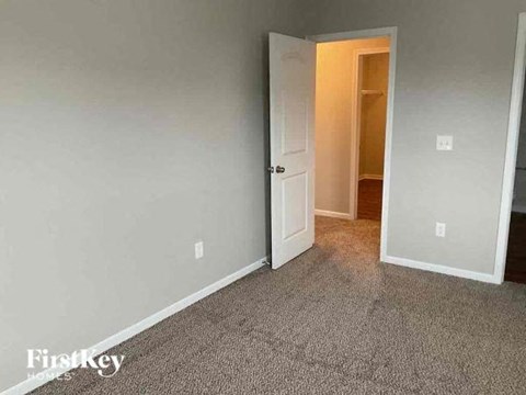 an empty room with a white door and a hallway