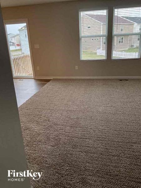 an empty living room with a rug in front of a window