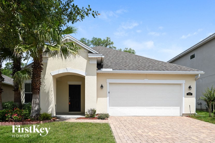 A house with a white garage door and a palm tree in front.