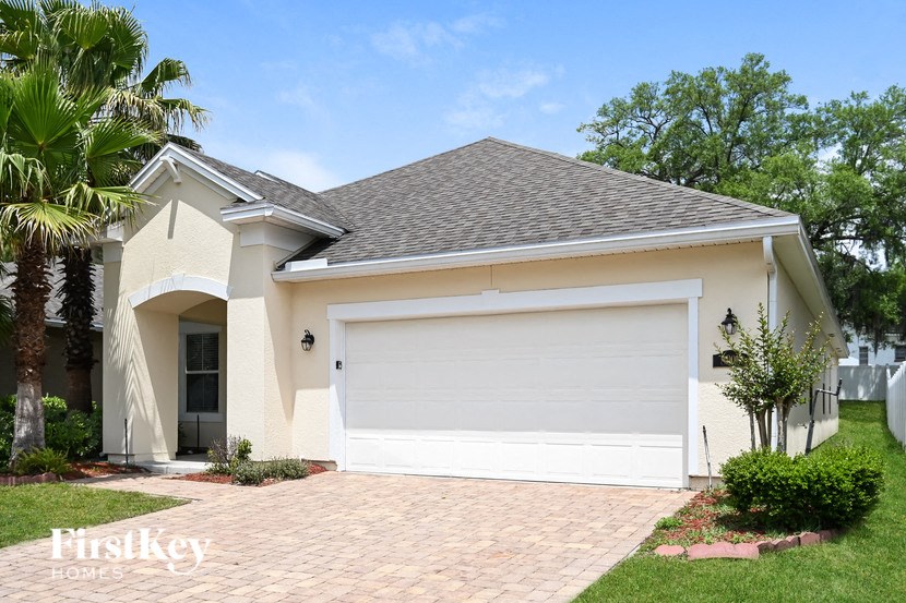 A house with a white garage door and a brick driveway.