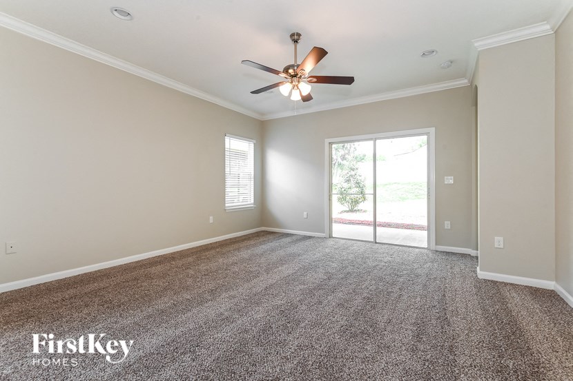 A spacious room with a ceiling fan and carpeted floor.