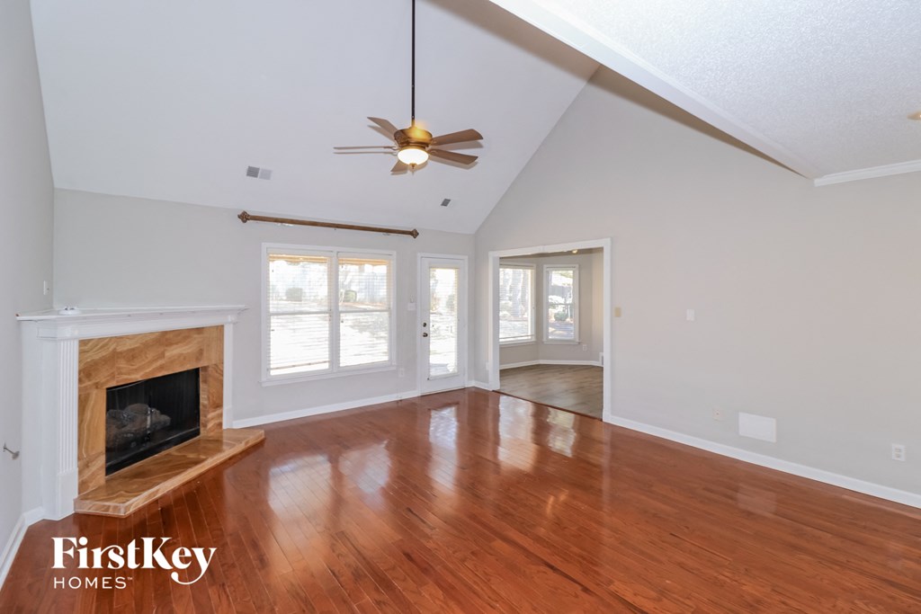 an empty living room with a fireplace and a ceiling fan